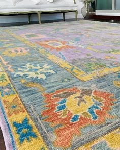 a multicolored area rug on the floor in front of a bed with pillows