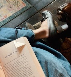 a person laying on the floor with their feet propped up and reading a book in front of them