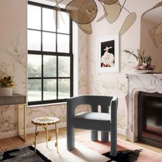 a living room with pink walls and floral wallpaper, a chair in front of a fireplace