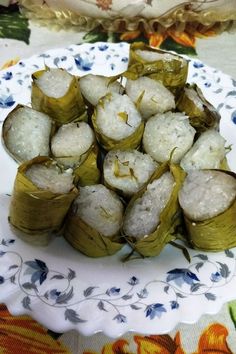 there are some food on the plate and one is wrapped in banana leaf wrappers