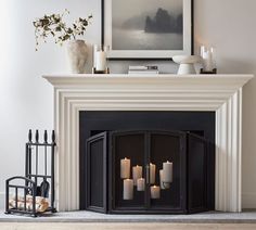 a fire place with candles on it in front of a painting and fireplace mantel