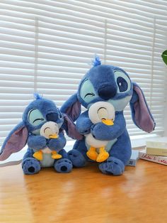 two stuffed animals sitting on top of a wooden table