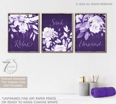 three purple and white floral prints hanging on a wall