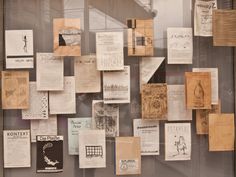 many pieces of paper are on display in a glass case with various types of papers attached to it