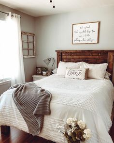 a bed with white sheets and pillows on top of it in a bedroom next to a window