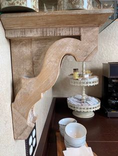 a wooden shelf with dishes on top of it and a mirror above the shelf in front of it