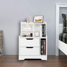 a white book shelf next to a bed in a room with gray walls and wooden floors