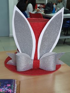 a red hat with silver glitter ears and bow on it, sitting on top of a table