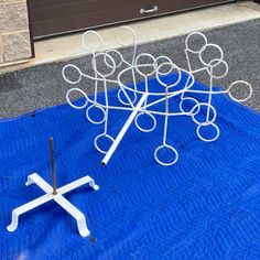 a metal sculpture sitting on top of a blue tarp next to a white cross