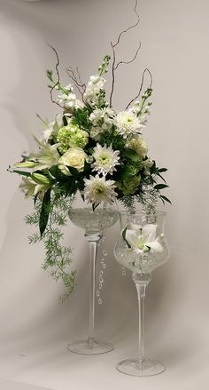 two wine glasses with flowers and greenery in them