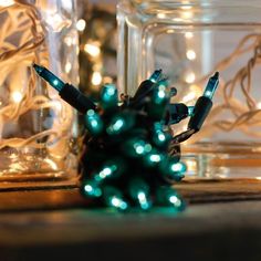 small christmas lights in glass jars with string lights on the top and bottom, sitting on a table