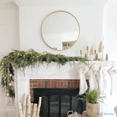 a fireplace decorated for christmas with greenery and stockings