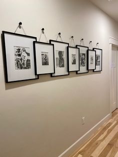 a hallway with pictures hanging on the wall and wood flooring in front of it