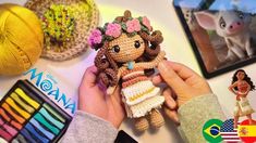 a person holding a doll in their hand next to some crocheted pictures and other items