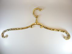 a gold colored coat hanger on a white wall