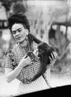 a woman holding a baby monkey in her arms