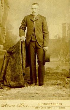 an old photograph of a man in a suit and tie holding a large piece of cloth