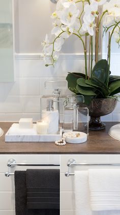 there is a vase with flowers and candles on the counter in front of the mirror