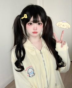 a woman with long black hair wearing a white jacket and holding up the peace sign