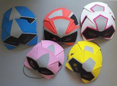 four different colored paper masks on a table