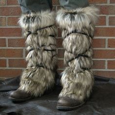 a pair of furry boots sitting on top of a black cloth next to a brick wall