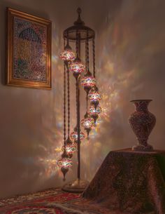 a chandelier hanging from the side of a wall next to a table with a vase on it