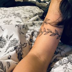 a woman laying on top of a bed with a tattoo on her arm