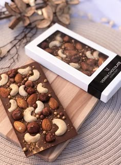 two pieces of chocolate with nuts are on a cutting board next to a white box