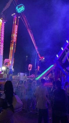 an amusement park at night with people standing around