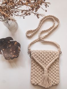 a crocheted purse sitting next to a vase with dried flowers and an object on the table