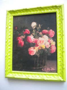 a painting of flowers in a basket on the wall next to a white wall with a green frame