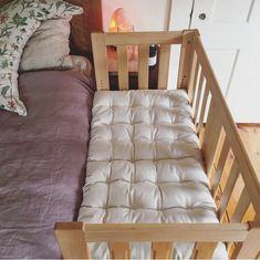 a wooden crib with a mattress on top of it