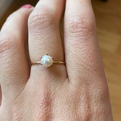 a woman's hand with a pearl ring on top of her finger and the other hand holding it