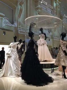 several mannequins dressed in black and white gowns on display at a fashion show