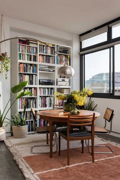 a dining room table and chairs with bookshelves in the background