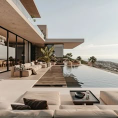 an outdoor living area with couches and tables next to a pool overlooking the ocean