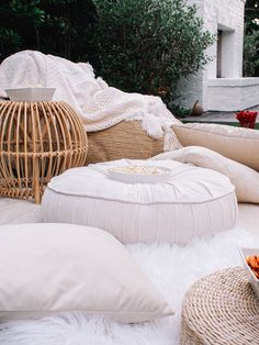 a bunch of pillows sitting on top of a white fluffy rug next to a bowl of food