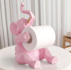 a pink elephant toilet paper holder sitting on top of a white table next to a chair