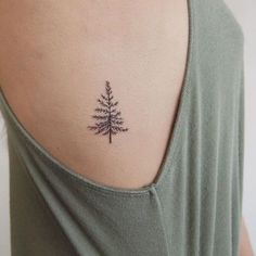 a small pine tree tattoo on the back of a woman's left shoulder and upper arm