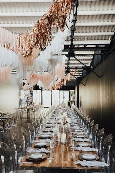 a long dining table with clear chairs and hanging chandeliers