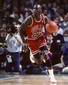 a basketball player dribbling the ball during a game with fans in the stands