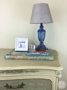 a blue vase sitting on top of a table next to a lamp and some books