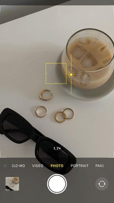 a pair of black sunglasses sitting on top of a table next to some gold rings