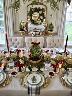 a dining room table set for christmas with holiday decorations and greenery on the tables