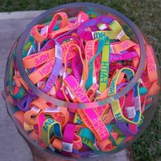 a person holding a bowl full of colorful bracelets