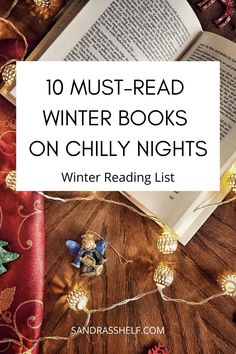 an open book sitting on top of a wooden table next to christmas decorations and lights