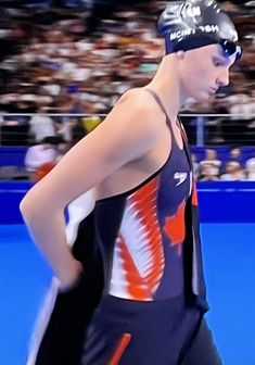 a man wearing a swim suit with an orange and white design on the side, standing in front of a crowd