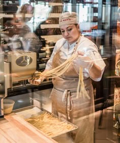 a woman in an apron is holding noodles