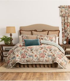 a bed with floral comforter and pillows in a room