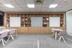 an empty meeting room with several tables and chairs in front of a large screen on the wall